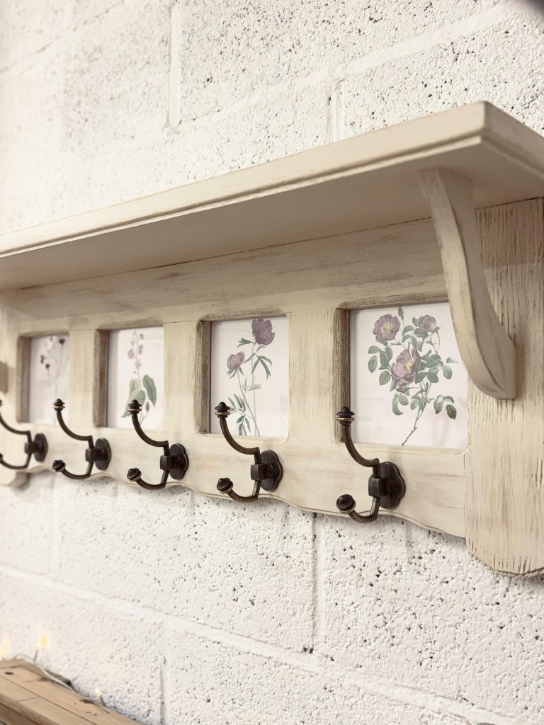 Étagère murale en bois rénovée avec cadres vitrés et crochets fonctionnels.