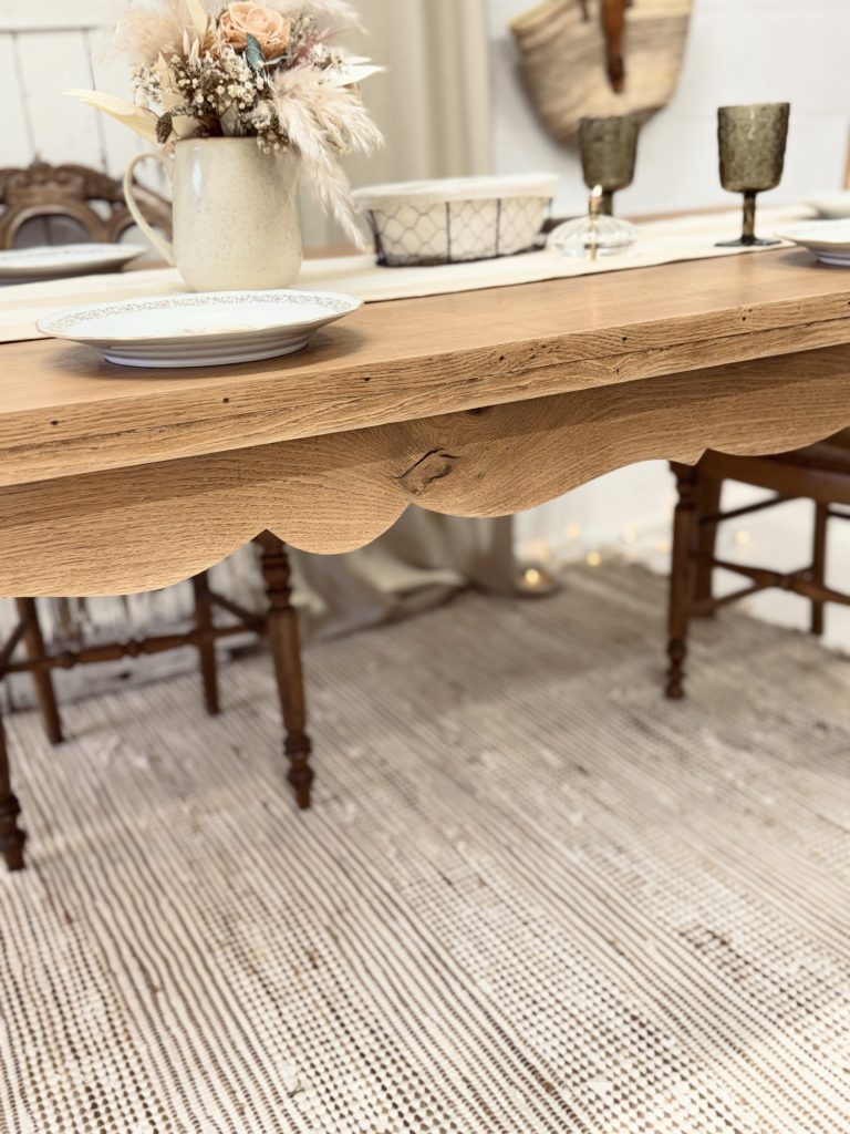 Table en bois clair restaurée avec rallonges pour accueillir de nombreux convives.