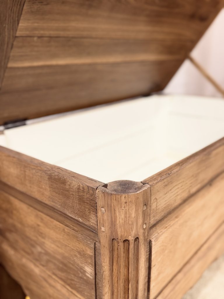 Banc coffre en chêne vu de trois quarts avec lignes authentiques et élégantes.